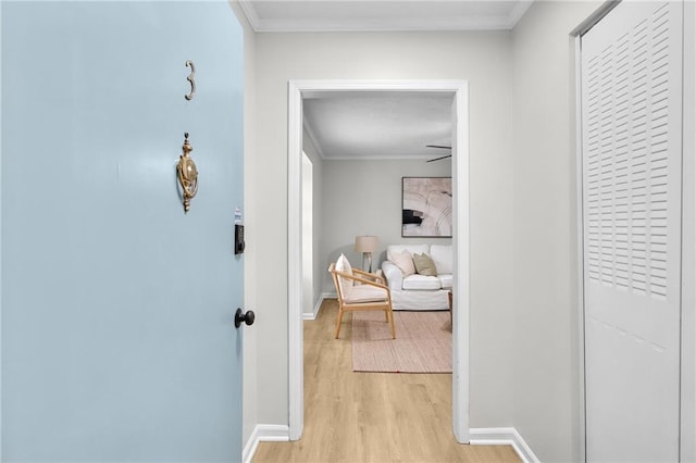 hall with ornamental molding, light wood-style flooring, and baseboards