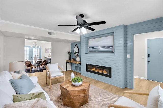 living area with ornamental molding, a fireplace, wood finished floors, and visible vents