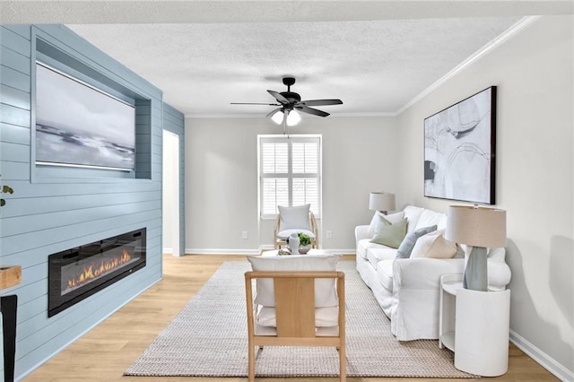 living room with a textured ceiling, ornamental molding, a fireplace, and light wood-style floors