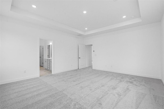 carpeted empty room featuring a tray ceiling