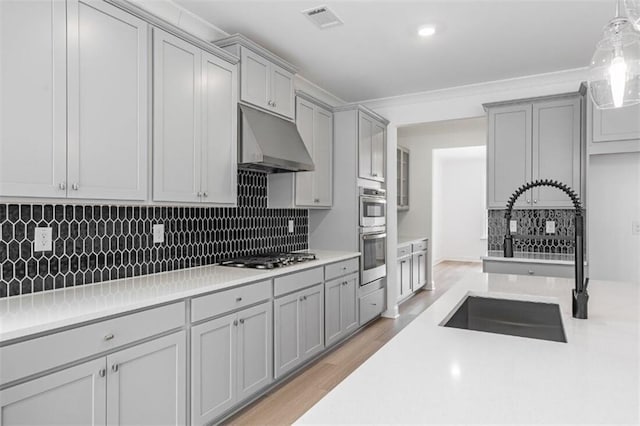 kitchen featuring wall chimney exhaust hood, sink, decorative light fixtures, stainless steel appliances, and decorative backsplash