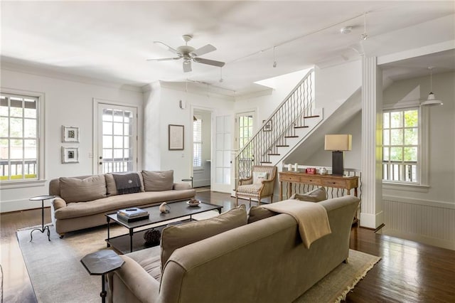 living area with stairs, wood finished floors, a healthy amount of sunlight, and a wainscoted wall