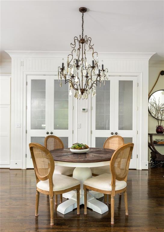 dining area with crown molding, wood finished floors, french doors, and a chandelier