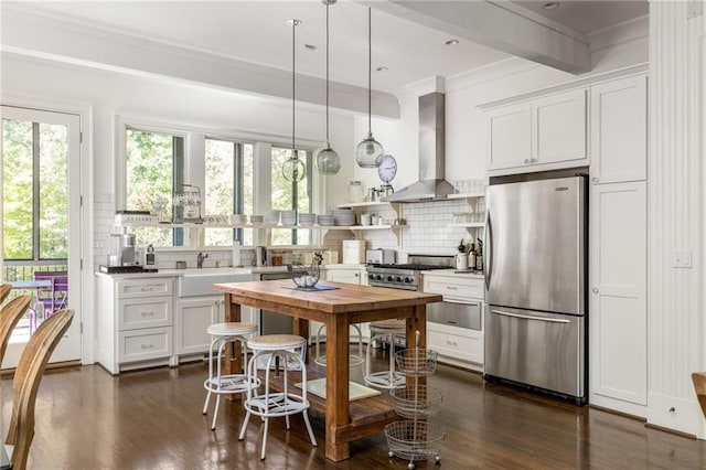 kitchen featuring wall chimney range hood, dark wood-style floors, tasteful backsplash, and freestanding refrigerator