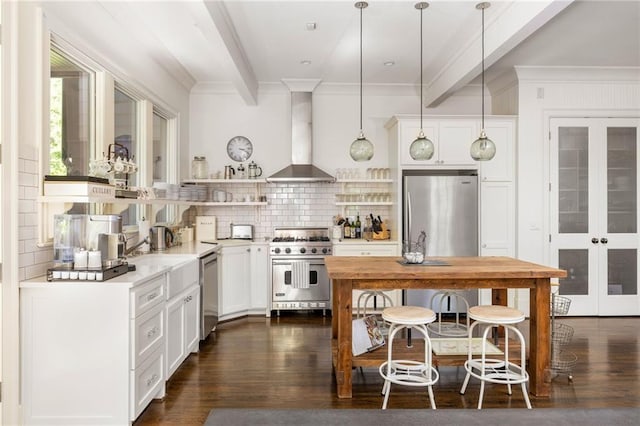 kitchen featuring open shelves, stainless steel appliances, decorative backsplash, beam ceiling, and wall chimney range hood