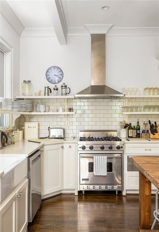 kitchen featuring crown molding, backsplash, wall chimney exhaust hood, appliances with stainless steel finishes, and dark wood finished floors