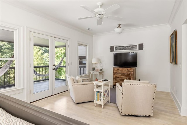 living room with light wood-style flooring, ornamental molding, baseboards, visible vents, and a ceiling fan