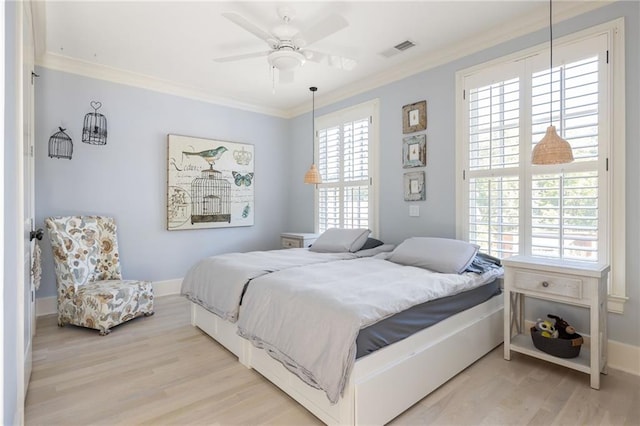 bedroom with crown molding, baseboards, light wood-style floors, visible vents, and a ceiling fan