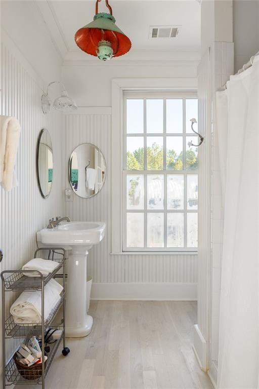 full bathroom featuring a sink, wood finished floors, baseboards, visible vents, and ornamental molding