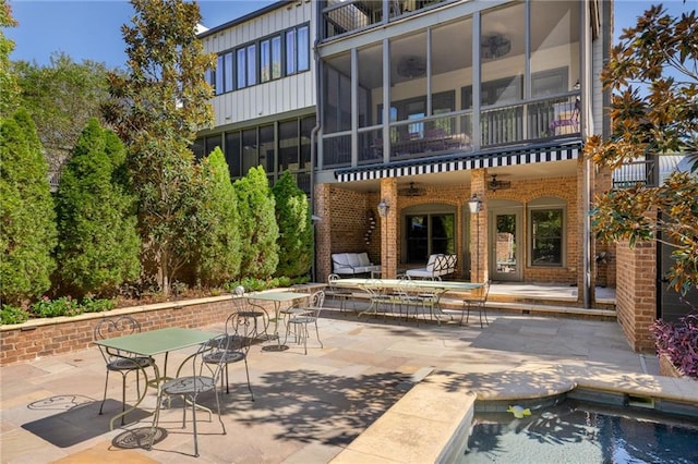 rear view of property with outdoor dining space, brick siding, a balcony, and a patio