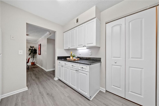 705 Beaufort Cir, Duluth, GA 30096 - kitchen featuring light wood finished floors, baseboards, white cabinets, dark countertops, and a textured ceiling