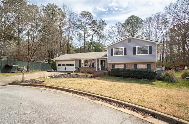 split level home with brick siding, fence, concrete driveway, a front yard, and a garage