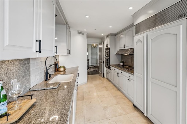 2660 Peachtree Rd NW Unit 23A, Atlanta, GA 30305 - kitchen with paneled refrigerator, stovetop, dark stone counters, backsplash, and under cabinet range hood