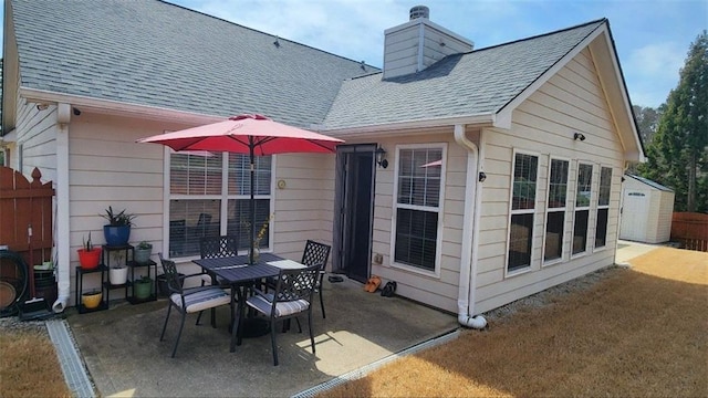 view of patio with outdoor dining area, a storage shed, an outdoor structure, and fence