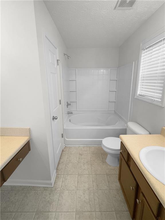 full bathroom with vanity, a textured ceiling, tile patterned flooring, shower / bathing tub combination, and toilet