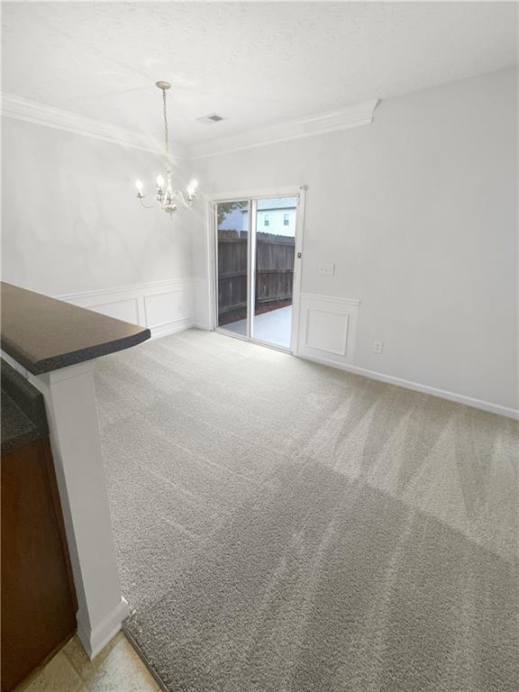 unfurnished dining area featuring carpet flooring, ornamental molding, and a chandelier