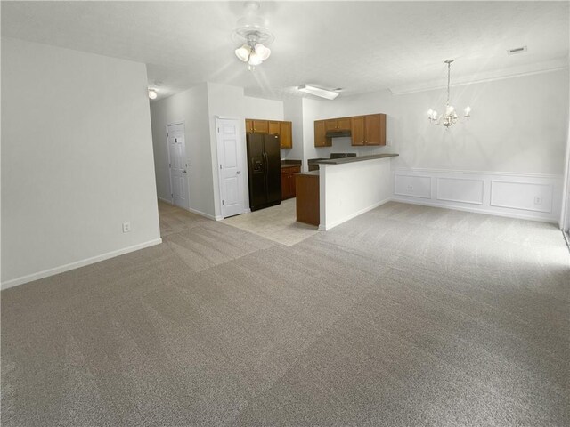 interior space with kitchen peninsula, decorative light fixtures, black appliances, light carpet, and a notable chandelier