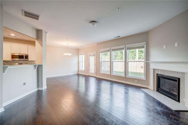 unfurnished living room featuring a notable chandelier and dark hardwood / wood-style flooring