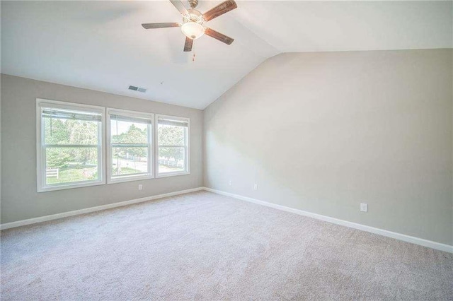 carpeted spare room featuring ceiling fan and vaulted ceiling