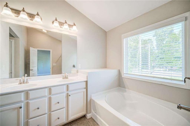 bathroom with vaulted ceiling, tile patterned floors, a wealth of natural light, and vanity