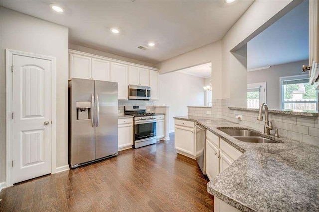 kitchen featuring stainless steel appliances, kitchen peninsula, sink, white cabinetry, and backsplash