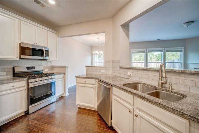 kitchen featuring light stone counters, stainless steel appliances, tasteful backsplash, white cabinets, and sink