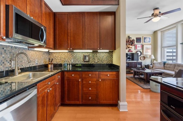 kitchen featuring tasteful backsplash, appliances with stainless steel finishes, light hardwood / wood-style floors, and sink