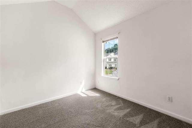 carpeted empty room featuring vaulted ceiling