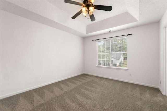 carpeted empty room featuring ceiling fan, a raised ceiling, and a textured ceiling