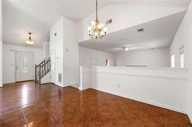 tiled spare room featuring lofted ceiling and a chandelier