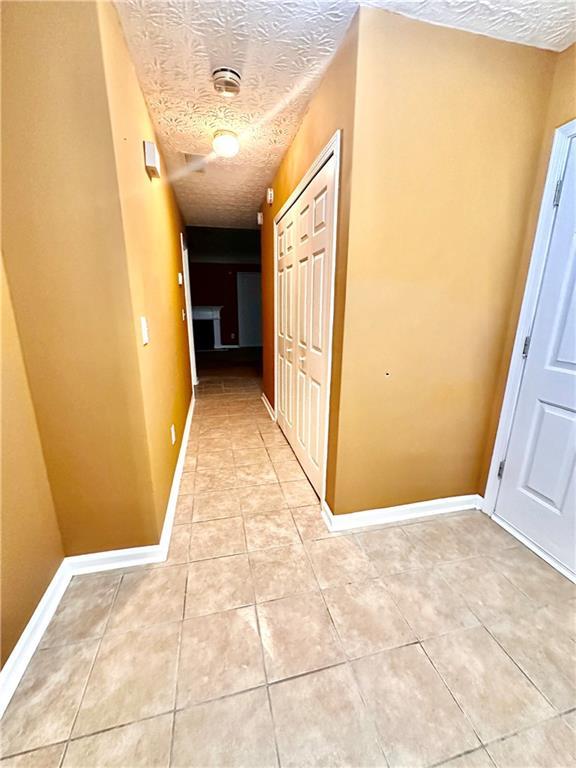 3793 Mays Ct SW, Atlanta, GA 30331 - hallway featuring a textured ceiling, light tile patterned floors, and baseboards