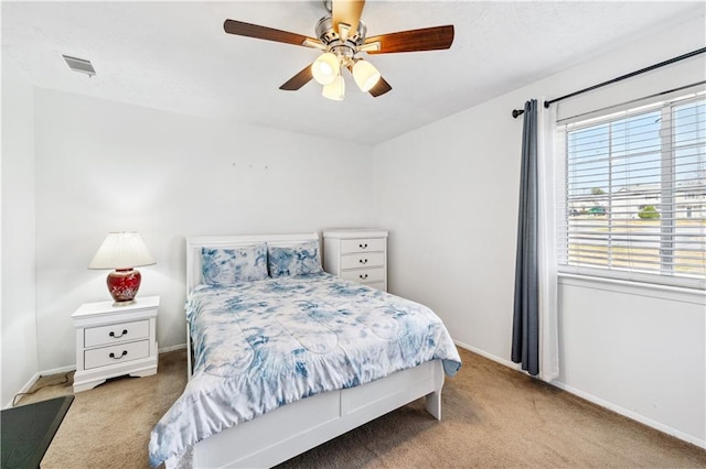 bedroom featuring a ceiling fan, visible vents, light carpet, and baseboards