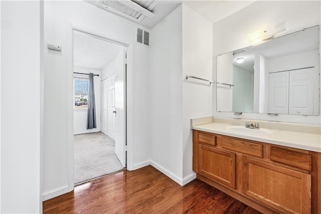 bathroom featuring visible vents, vanity, baseboards, and wood finished floors