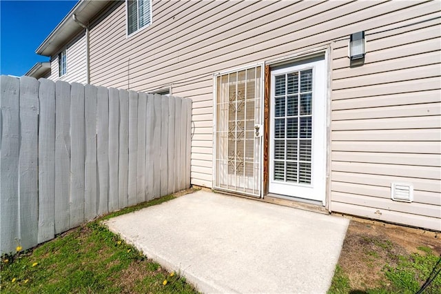 view of exterior entry featuring a patio area and fence