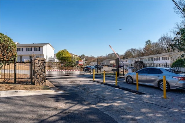 view of road with a residential view, a gate, curbs, and a gated entry