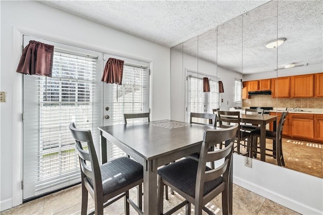 dining area featuring a wealth of natural light, a textured ceiling, and baseboards