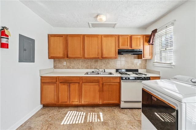 kitchen with under cabinet range hood, a sink, light countertops, white gas range oven, and washer / dryer