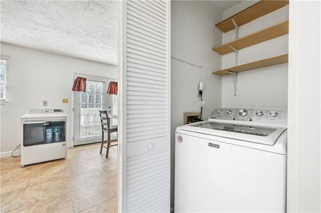 clothes washing area featuring light tile patterned floors, washer / clothes dryer, and a textured ceiling