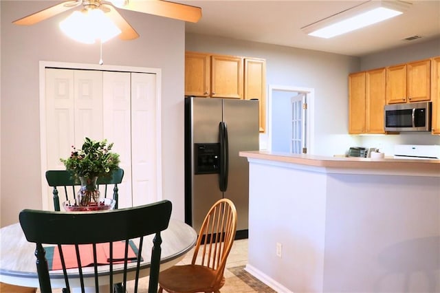 kitchen with light brown cabinetry, stainless steel appliances, kitchen peninsula, and ceiling fan