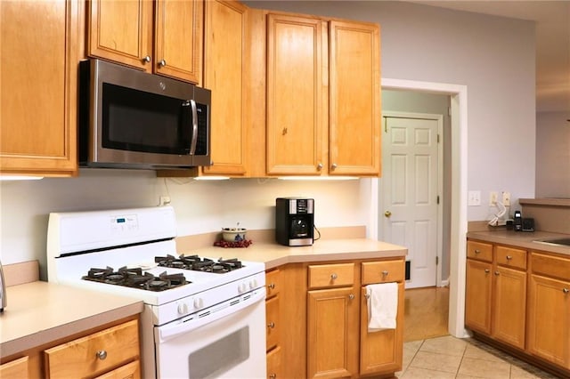 kitchen featuring white range with gas stovetop and light tile patterned floors