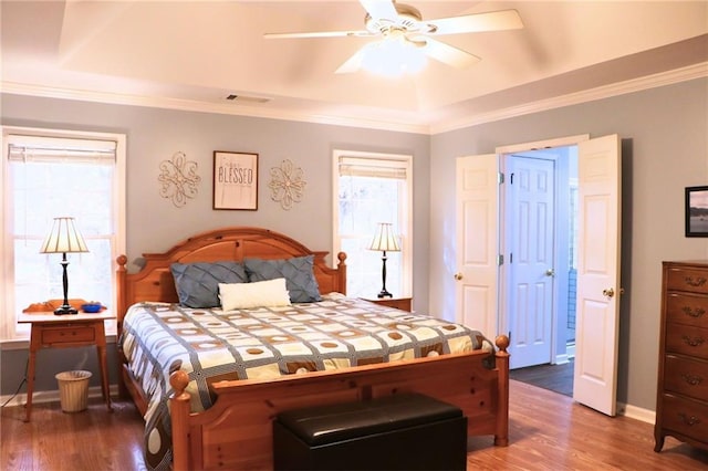 bedroom with multiple windows, wood-type flooring, and ornamental molding