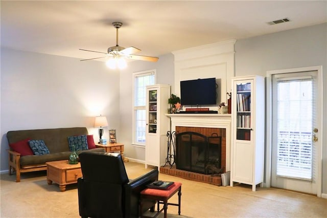 carpeted living room with a brick fireplace and ceiling fan