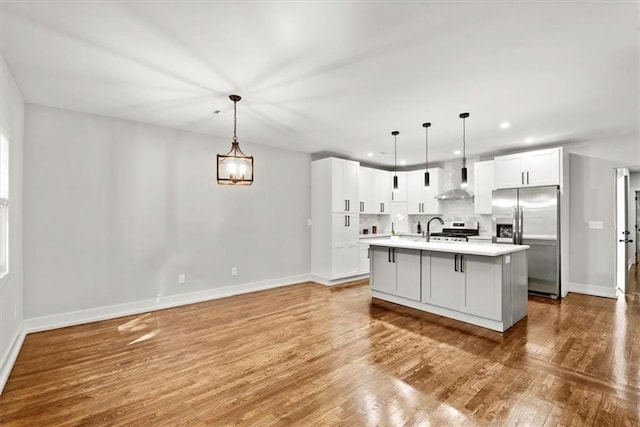 kitchen featuring appliances with stainless steel finishes, white cabinetry, pendant lighting, and an island with sink