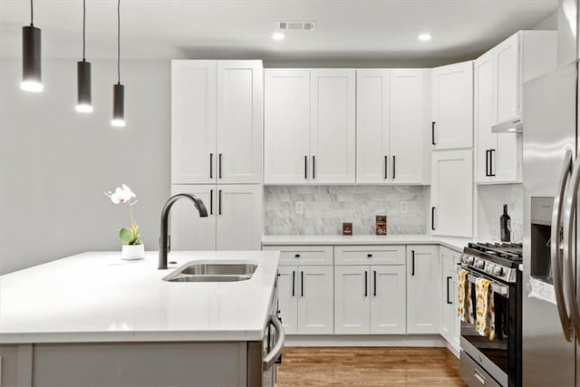 kitchen with white cabinetry, sink, stainless steel appliances, tasteful backsplash, and pendant lighting