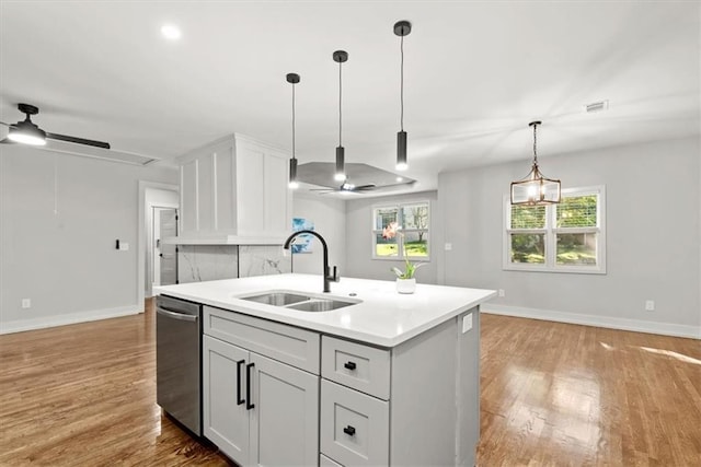 kitchen featuring hardwood / wood-style floors, ceiling fan with notable chandelier, a kitchen island with sink, and sink