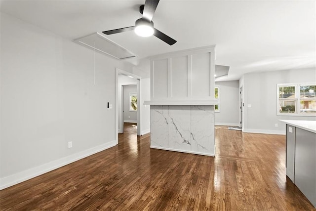 unfurnished living room featuring ceiling fan and dark wood-type flooring