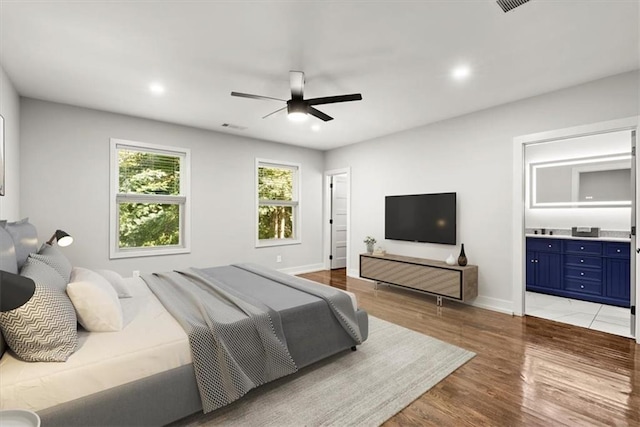 bedroom with ceiling fan, light hardwood / wood-style floors, and ensuite bathroom