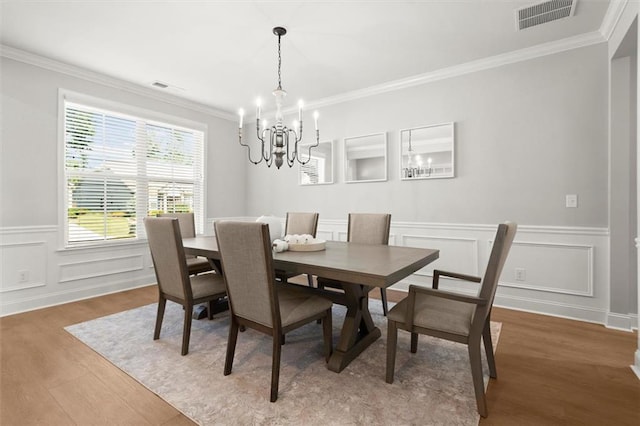 7410 Ansley View Ln, Cumming, GA 30028 - dining area with a chandelier, wood finished floors, ornamental molding, a wainscoted wall, and a decorative wall