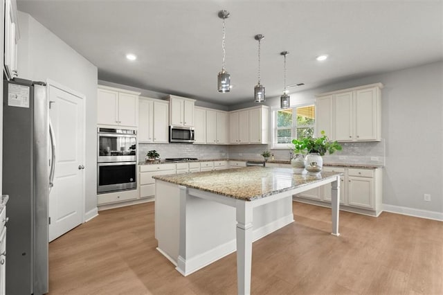 7410 Ansley View Ln, Cumming, GA 30028 - kitchen with stainless steel appliances, light wood-type flooring, a kitchen island, decorative backsplash, and a kitchen breakfast bar