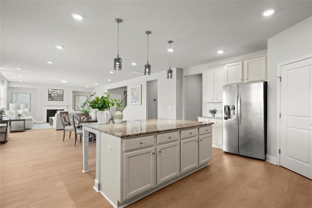 7410 Ansley View Ln, Cumming, GA 30028 - kitchen with stainless steel fridge, light wood-style flooring, a kitchen island, recessed lighting, and open floor plan